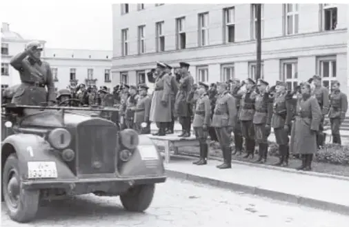 Fotografía histórica en blanco y negro de militares alemanes con uniformes de época frente a un vehículo automotor, en un acto público, ilustrando el militarismo descrito.