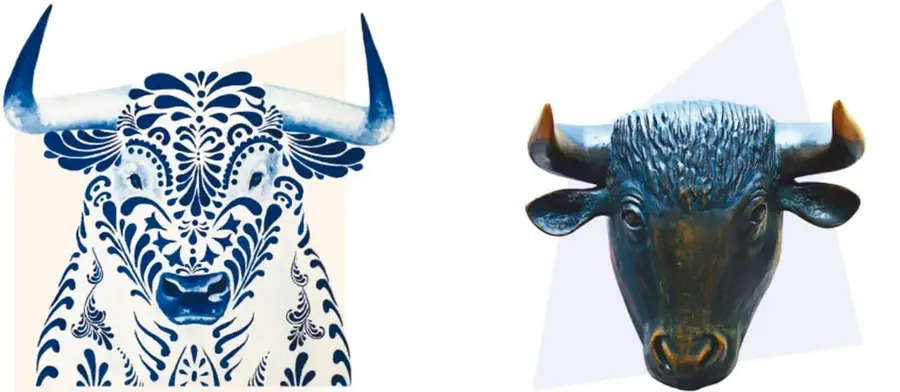 Cabeza de toro en cerámica blanca decorada con flores y grecas azules, estilo talavera, sobre fondo color crema.