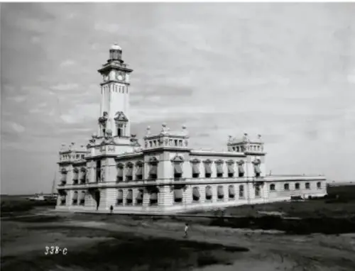 Fotografía antigua en blanco y negro de un palacio municipal con torre y reloj, sin entorno urbano desarrollado.