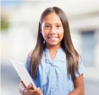 Fotografía de una estudiante sonriente con uniforme escolar sosteniendo un cuaderno, en un entorno escolar.