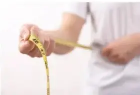 Persona midiendo su cintura con una cinta métrica, ilustrando la medición del exceso de peso.