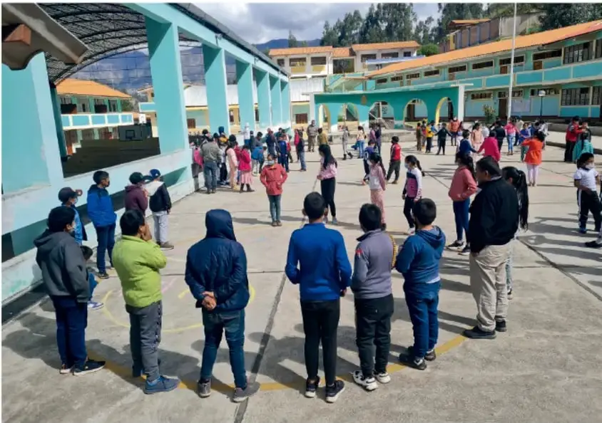 Fotografía de estudiantes de primaria formados en el patio de una escuela, con uniforme deportivo, durante una actividad colectiva.