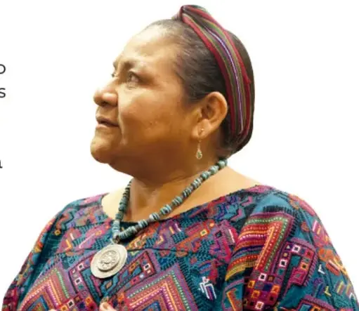 Retrato de Rigoberta Menchú adulta, de perfil, con huipil tradicional multicolor, collar con medalla grande y cinta roja en el cabello.