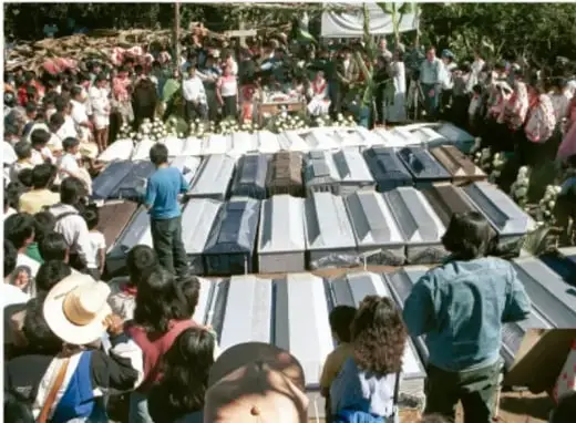 Fotografía de una comunidad indígena reunida alrededor de ataúdes, probablemente en Acteal, Chiapas.