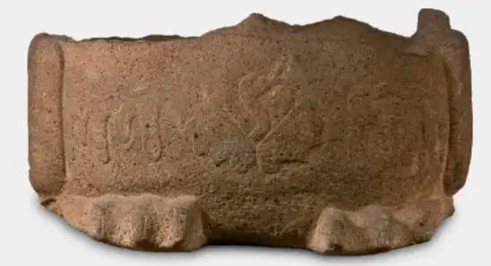 Escultura humano-felina con manoplas, figura de piedra que combina rasgos humanos y felinos.