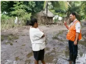 Fotografía de dos personas conversando al aire libre en un entorno rural, una de ellas con vestimenta naranja.