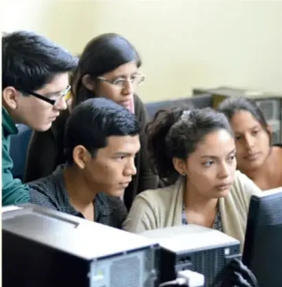 Grupo de estudiantes reunidos frente a una computadora, revisando y organizando la información del proyecto.