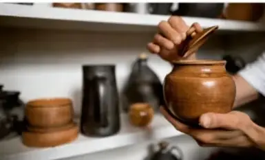 Estantería con piezas de cerámica artesanal (ollas y vasijas de barro) en un taller.