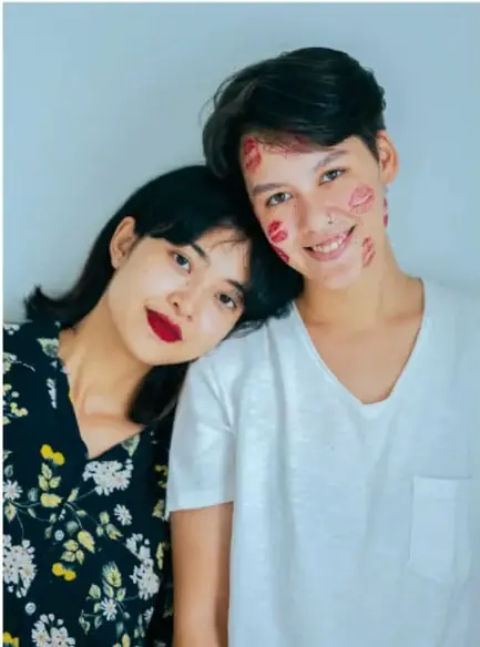Fotografía de una joven y un joven sonriendo, con marcas rojas en las mejillas, que ilustra la diversidad y la expresión libre de la identidad.