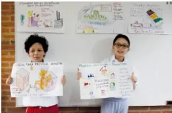Dos niñas sostienen carteles con dibujos sobre fenómenos naturales.