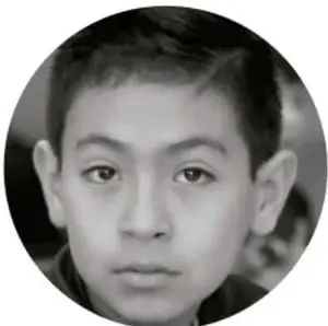 Fotografía en blanco y negro de un niño de primaria con expresión pensativa, mirando de frente.
