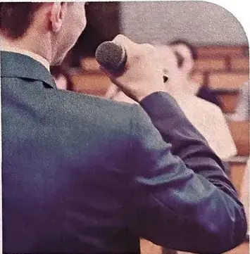 Fotografía de una persona utilizando un micrófono frente a otra persona, relacionada con el debate o la comunicación oral.