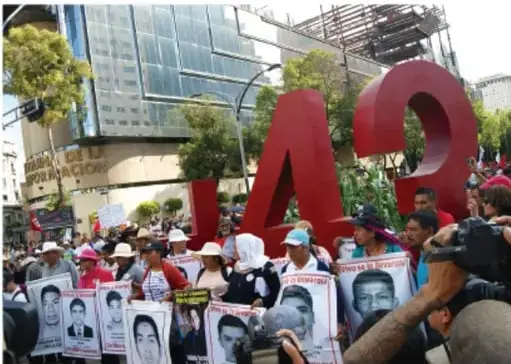 Plaza pública con muchas personas reunidas, algunas con pancartas.