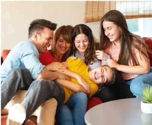 Fotografía de una familia (padres, dos hijas y un hijo) reunida y sonriente sobre un sillón, en actitud de convivencia, ilustrando la actividad 'Situaciones para aprender en familia'.