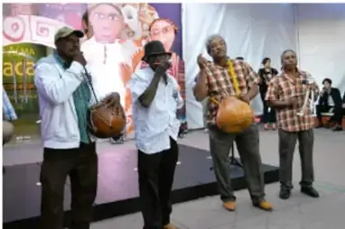 Grupo de hombres afromexicanos tocando tambores y realizando una presentación musical en un recinto público.