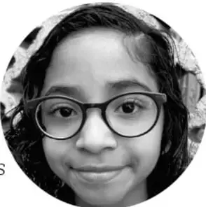 Fotografía circular en blanco y negro de una niña sonriente que usa lentes redondos.