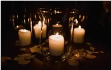 Fotografía de varias velas encendidas en un ambiente oscuro, mostrando la luz y calor producidos por la combustión.