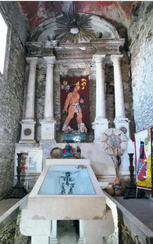 Interior del Museo Tumba de Cuauhtémoc con el altar, el féretro con los restos del tlatoani bajo una vitrina y ofrendas prehispánicas.