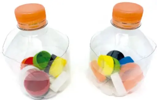 Dos botellas de plástico con tapa naranja que contienen materiales de colores en su interior, usadas como instrumentos musicales.
