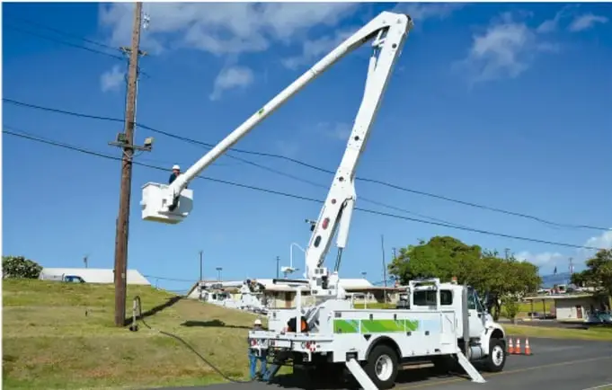 Camión de servicio con brazo elevador y una varilla a tierra, trabajando cerca de un poste de luz.