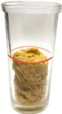 Vaso transparente con pasta (cereales) dentro y una marca roja ovalada que indica el nivel de la porción.