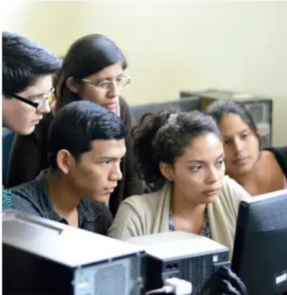 Grupo de estudiantes observando una pantalla de computadora, colaborando en la creación del material de divulgación.