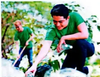 Estudiantes y adultos participan en una actividad comunitaria de trabajo en un espacio verde.
