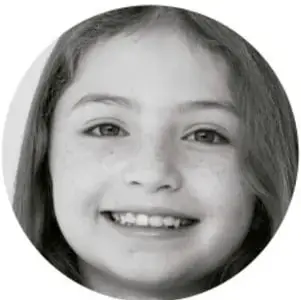 Fotografía circular del rostro sonriente de una niña de primaria.