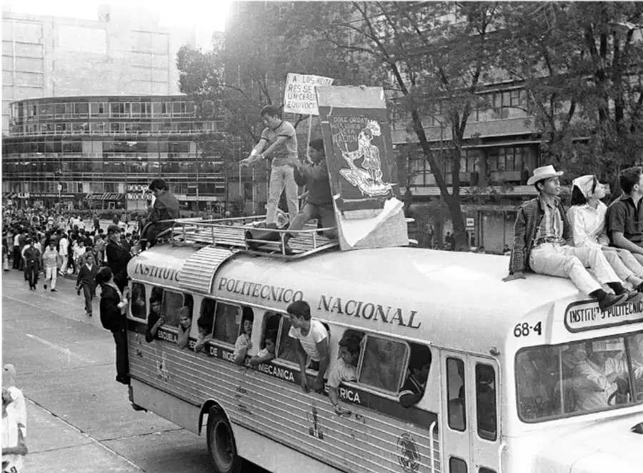 Fotografía en blanco y negro de un autobús del Instituto Politécnico Nacional con estudiantes sobre el techo y en las ventanillas, sosteniendo pancartas. Se lee "INSTITUTO POLITÉCNICO NACIONAL", "ESCUELA SUPERIOR DE INGENIERÍA MECÁNICA" y "68-4". Al fondo, edificios y una multitud.