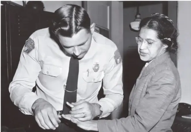 Fotografía en blanco y negro de Rosa Parks siendo procesada por un policía que toma sus huellas digitales en una oficina, al momento de su arresto.