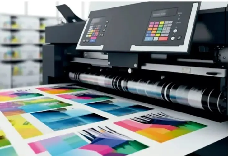 Fotografía de una impresora o máquina de impresión offset produciendo hojas con imágenes a todo color (gama completa de colores sobre papel)