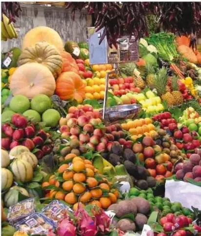 Fotografía de un puesto de mercado con frutas, verduras, calabazas y otros alimentos frescos de la comunidad.