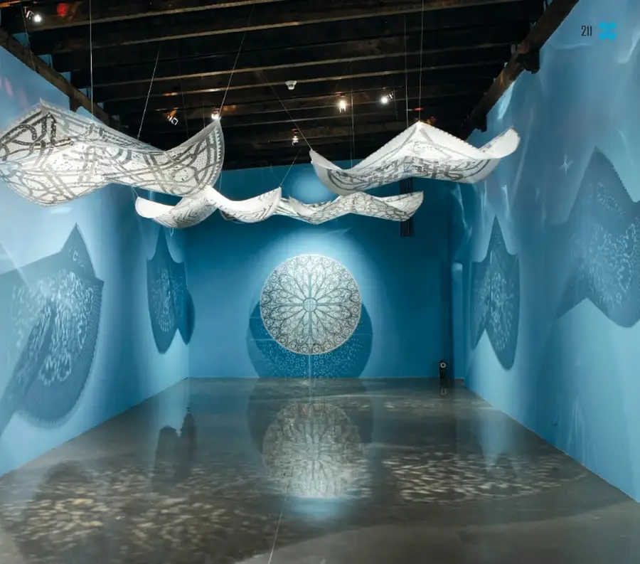 Obra *Anémonas de luz* (2008): sala con paredes azules, cielo raso de vigas de madera, capós o cubiertas de carro blancas talladas y colgadas del techo como esculturas, que proyectan sombras circulares ornamentadas sobre las paredes y el piso brillante.