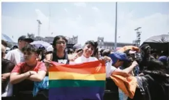 Grupo de personas en una marcha con una bandera multicolor, ilustrando la valoración de creencias y pensamientos diversos.