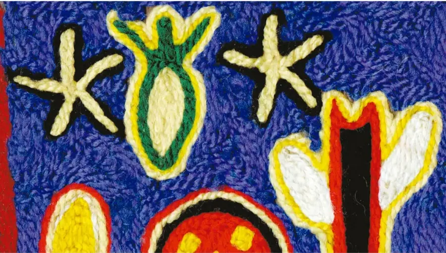 Fotografía de un cuadro de estambre estilo Niérika: sobre fondo azul de hebras apretadas destacan figuras bordadas en amarillo, verde, rojo, negro y blanco (formas estrelladas, una figura vegetal central, una figura con cuernos o cactus y un rostro).