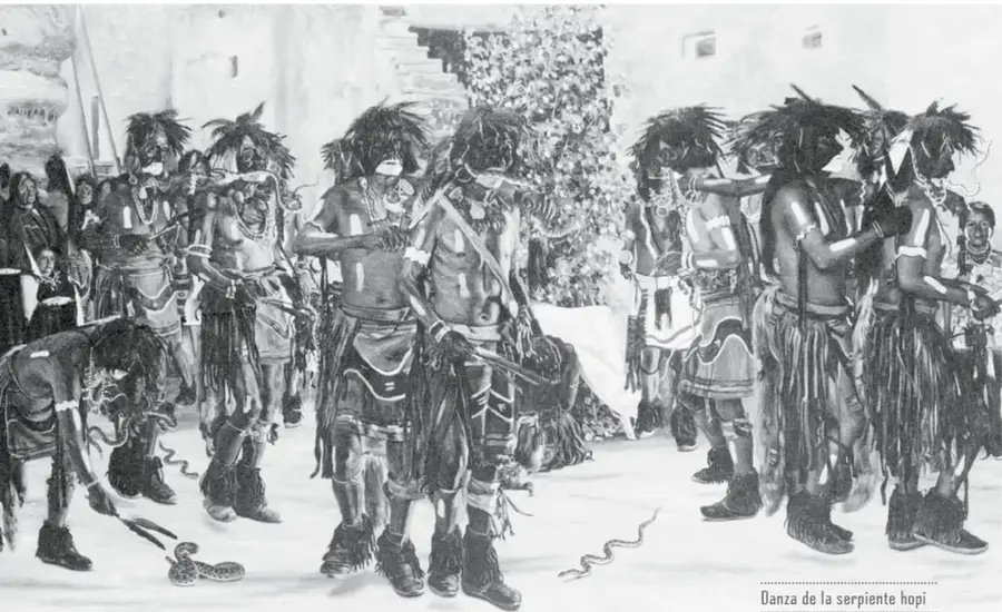 Fotografía en blanco y negro de la «Danza de la serpiente hopi»: varios hombres con faldas de flecos y cuerpos pintados bailan en la plaza; en el suelo se ven serpientes.