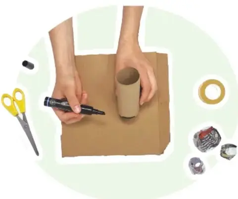 Fotografía de manos pegando cinta adhesiva a una bola arrugada de papel; se ven tijeras amarillas, un rollo de cinta adhesiva y bolas de papel pequeñas.