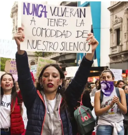 Mujer joven en una marcha sosteniendo un cartel que dice 'NUNCA VOLVERÁN A TENER LA COMODIDAD DE NUESTRO SILENCIO'.