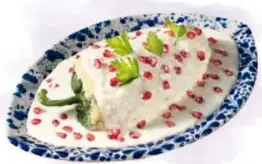Fotografías de un chile en nogada con granada en plato de Talavera, una charola de tamales guichepos de hoja de elote y un pipián de pollo.