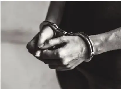 Manos esposadas en blanco y negro, símbolo de privación de la libertad.