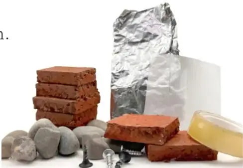 Fotografía de objetos pequeños: ladrillitos rojos apilados, piedras grises, clavos, papel aluminio, plástico blanco y un trozo de goma amarilla.