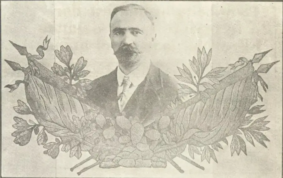 Retrato fotográfico de Francisco I. Madero, de traje oscuro y corbata, enmarcado por ramas de laurel y encino entrelazadas.