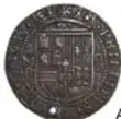 Fotografía del anverso de una moneda macuquina colonial con escudo.