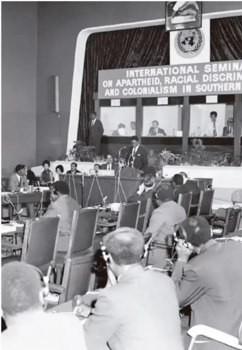 Fotografía en blanco y negro de una sesión de la ONU titulada "International Seminar on Apartheid, Racial Discrimination and Colonialism in Southern Africa", con delegados sentados y un orador en la tribuna.