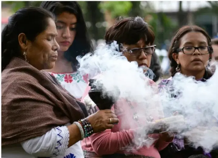 Fotografía de un grupo de mujeres en comunidad realizando un ritual con humo (quema de resina o copal), ilustrando elementos intangibles del patrimonio cultural: tradiciones y rituales transmitidos entre generaciones.