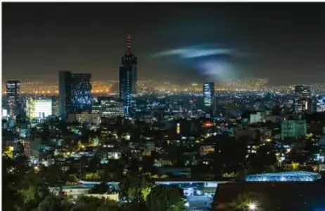 Fotografía nocturna de una ciudad con destellos luminosos en el cielo, asociada a los temblores.