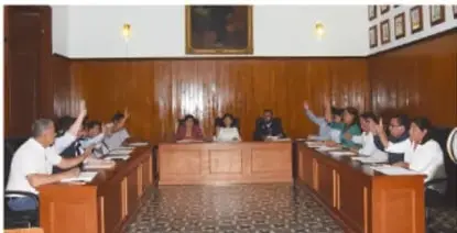Estudiante usando una computadora en un aula de cómputo con otros compañeros al fondo.