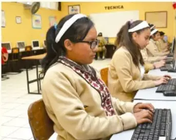 Fotografía de dos mujeres trabajando en computadoras en una oficina.