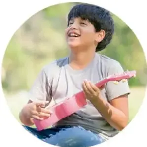 Niño sonriente tocando una guitarra de juguete.