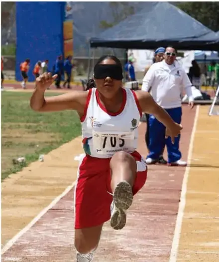 Atleta con discapacidad visual compitiendo en pista con vendado en los ojos, ilustrando la inclusión de personas con discapacidades.